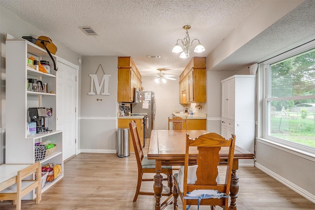 423 Parkview Dr, Burleson, TX 76028 - dining space featuring a textured ceiling, a chandelier, light wood finished floors, baseboards, and a ceiling fan