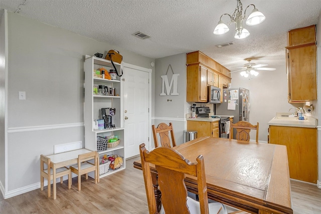 423 Parkview Dr, Burleson, TX 76028 - dining space featuring light wood-style flooring, a textured ceiling, a ceiling fan, a chandelier, and baseboards