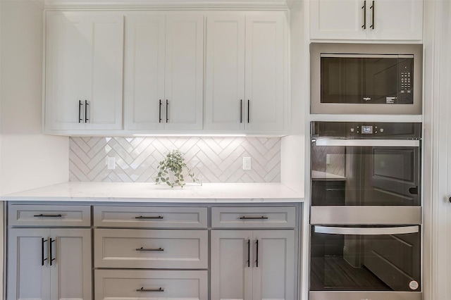 823 Wind River Pass, Azle, TX 76020 - kitchen with double oven, built in microwave, decorative backsplash, light stone counters, and gray cabinetry