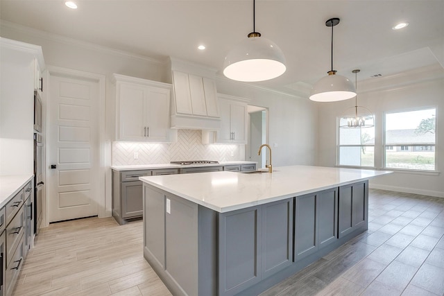 823 Wind River Pass, Azle, TX 76020 - kitchen with gray cabinetry, appliances with stainless steel finishes, a sink, backsplash, and an island with sink