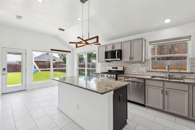 826 Ashley Pl, Mesquite, TX 75181 - kitchen with appliances with stainless steel finishes, a sink, gray cabinetry, vaulted ceiling, and a kitchen island