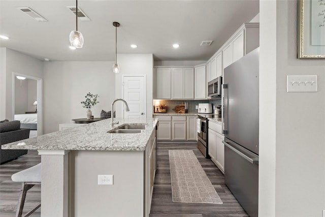 1512 Elise Ave, Waco, TX 76706 - kitchen with stainless steel appliances, a sink, dark wood-style flooring, decorative backsplash, and a kitchen breakfast bar