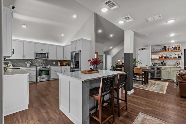 1617 Versailles Dr, Richardson, TX 75081 - kitchen featuring appliances with stainless steel finishes, wine cooler, vaulted ceiling, light stone counters, and tasteful backsplash