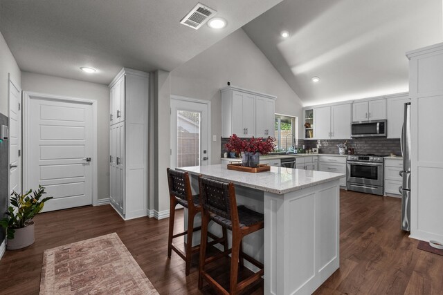 1617 Versailles Dr, Richardson, TX 75081 - kitchen featuring appliances with stainless steel finishes, light stone counters, decorative backsplash, white cabinets, and high vaulted ceiling