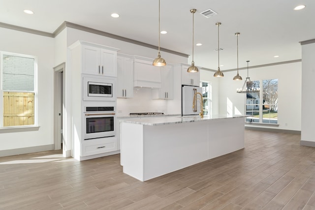 840 Northwood Rd, Fort Worth, TX 76107 - kitchen with white appliances, crown molding, a kitchen island with sink, white cabinets, and light wood finished floors