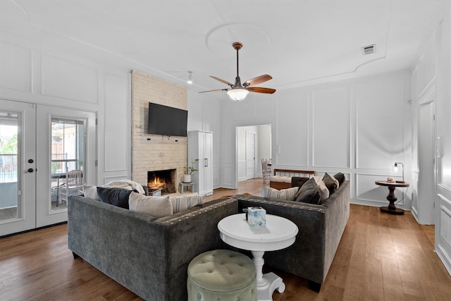 1610 Alpine Pass, Lewisville, TX 75077 - living area with a decorative wall, french doors, a brick fireplace, wood finished floors, and a ceiling fan