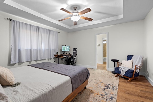 1610 Alpine Pass, Lewisville, TX 75077 - bedroom featuring a tray ceiling, wood finished floors, connected bathroom, a ceiling fan, and an office area