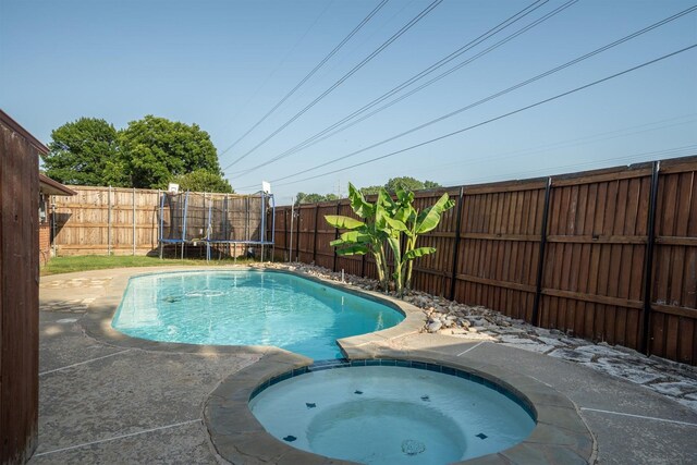 1610 Alpine Pass, Lewisville, TX 75077 - view of pool featuring a trampoline, a fenced backyard, and a pool with connected hot tub