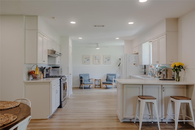 2712 Larkin Ave, Fort Worth, TX 76133 - kitchen with gas range, under cabinet range hood, freestanding refrigerator, a sink, and a breakfast bar