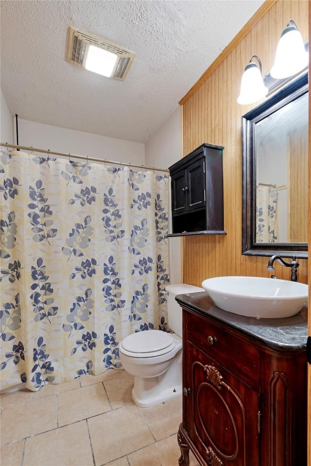 635 N Center St, Blossom, TX 75416 - bathroom with vanity, a textured ceiling, toilet, wooden walls, and tile patterned flooring