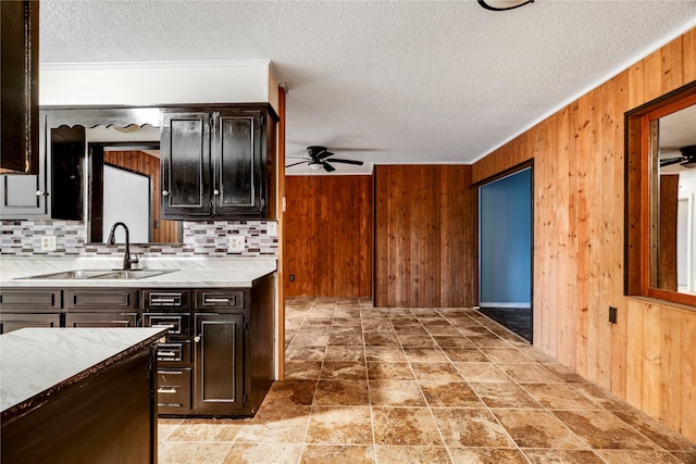 635 N Center St, Blossom, TX 75416 - kitchen with a sink, ceiling fan, wooden walls, tasteful backsplash, and a textured ceiling