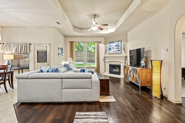2508 Pioneer Dr, Denton, TX 76210 - living room with a ceiling fan, arched walkways, a raised ceiling, dark wood finished floors, and a fireplace with raised hearth