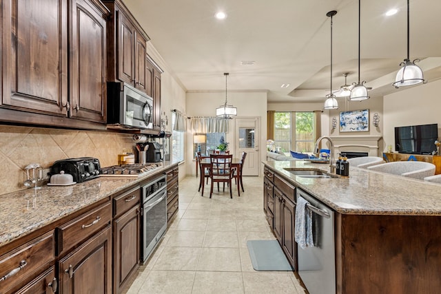 2508 Pioneer Dr, Denton, TX 76210 - kitchen featuring stainless steel appliances, a sink, tasteful backsplash, open floor plan, and light stone counters