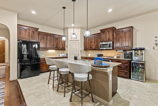 2508 Pioneer Dr, Denton, TX 76210 - kitchen with black fridge, stainless steel microwave, beverage cooler, arched walkways, and dark brown cabinetry