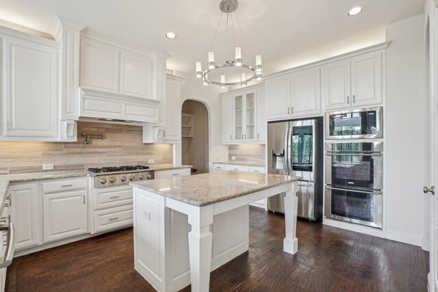 4534 Whispering Lake Dr, Frisco, TX 75036 - kitchen featuring appliances with stainless steel finishes, arched walkways, glass insert cabinets, dark wood-style floors, and recessed lighting
