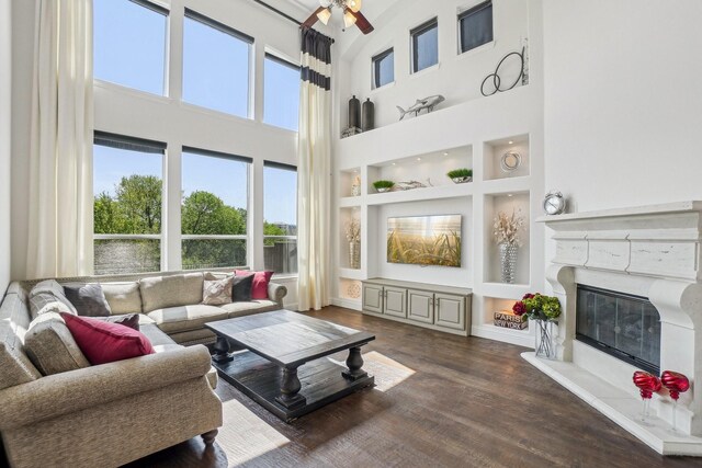 4534 Whispering Lake Dr, Frisco, TX 75036 - living area featuring wood finished floors, ceiling fan, a chandelier, a glass covered fireplace, and a towering ceiling