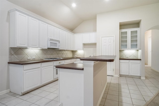 8393 Davis Dr, Frisco, TX 75036 - kitchen featuring white appliances, dark countertops, backsplash, light tile patterned floors, and vaulted ceiling
