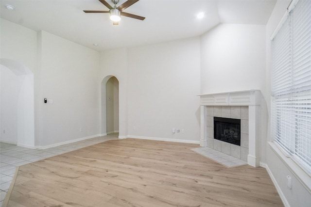 8393 Davis Dr, Frisco, TX 75036 - unfurnished living room with arched walkways, a ceiling fan, wood finished floors, a fireplace, and high vaulted ceiling