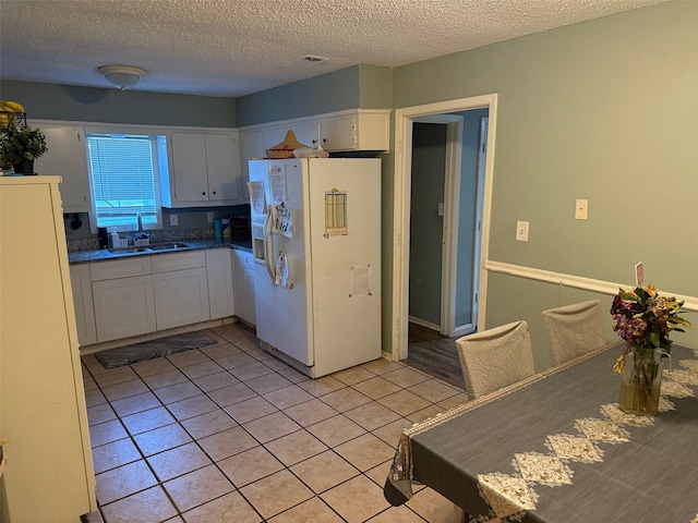 501 Towne House Ln, Richardson, TX 75081 - kitchen with white fridge with ice dispenser, white cabinetry, a sink, a textured ceiling, and light tile patterned flooring