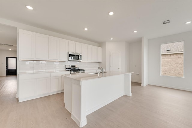 1802 Golden Sq, Cedar Hill, TX 75116 - kitchen featuring stainless steel appliances, a sink, a kitchen island with sink, light wood-type flooring, and white cabinetry