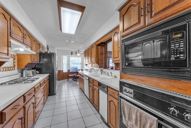 227 Meadowlark Ln, Duncanville, TX 75137 - kitchen with black appliances, a textured ceiling, brown cabinetry, light countertops, and decorative backsplash