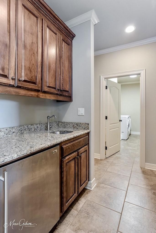 1010 Toledano Cir, Shreveport, LA 71106 - kitchen featuring a sink, crown molding, baseboards, light stone countertops, and separate washer and dryer