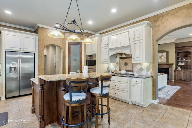 1010 Toledano Cir, Shreveport, LA 71106 - kitchen with stainless steel appliances, arched walkways, light stone countertops, a kitchen island, and a kitchen bar