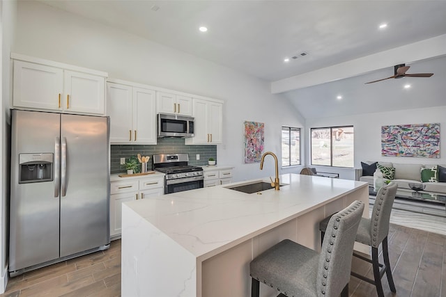 5607 Emrose Cir, Dallas, TX 75227 - kitchen featuring appliances with stainless steel finishes, a sink, wood finished floors, white cabinetry, and an island with sink