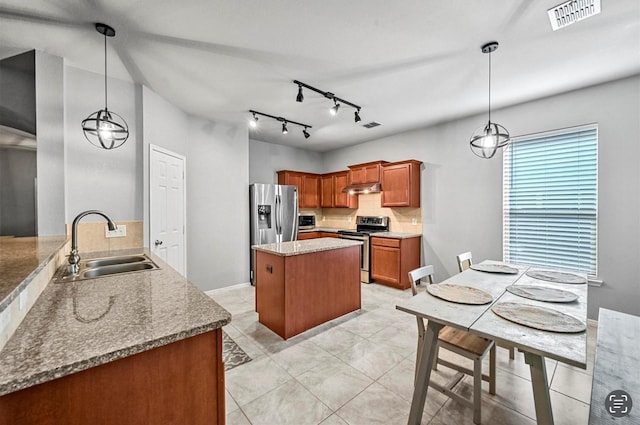 405 Cypress Hill Dr, Mckinney, TX 75071 - kitchen with appliances with stainless steel finishes, a sink, under cabinet range hood, brown cabinets, and decorative backsplash