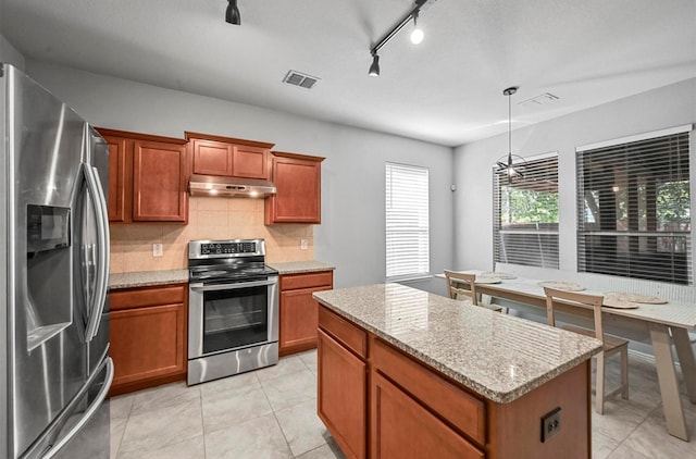 405 Cypress Hill Dr, Mckinney, TX 75071 - kitchen with appliances with stainless steel finishes, under cabinet range hood, a center island, and brown cabinets