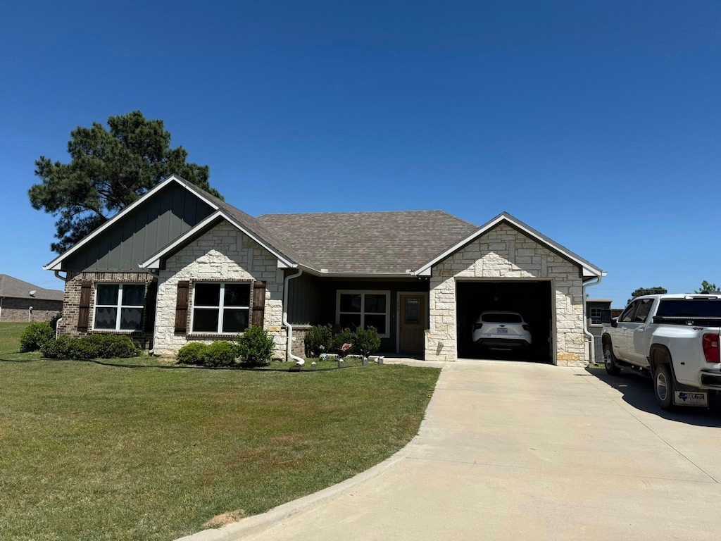 207 Mill St, Emory, TX 75440 - view of front of home with stone siding, a garage, driveway, a front yard, and board and batten siding