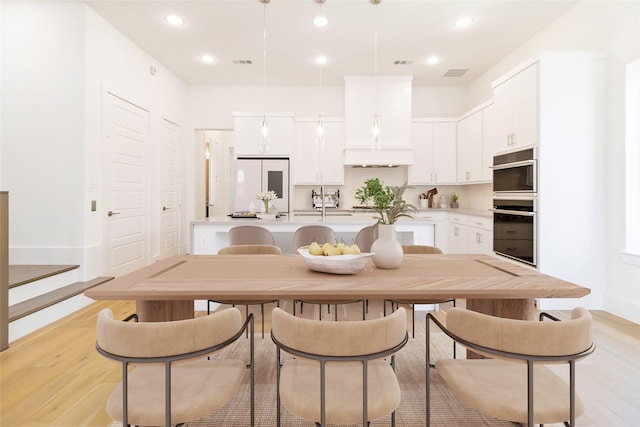 7844 Secluded Ave, Plano, TX 75024 - kitchen with white refrigerator, stainless steel double oven, light countertops, a kitchen island with sink, and light wood finished floors