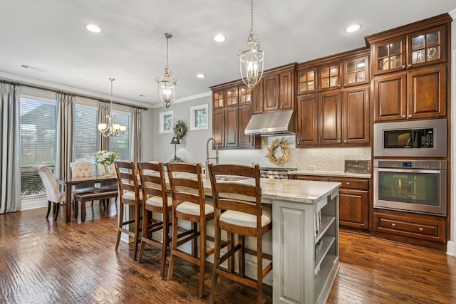 3308 Linkwood, The Colony, TX 75056 - kitchen with stainless steel appliances, under cabinet range hood, a chandelier, ornamental molding, and a center island with sink
