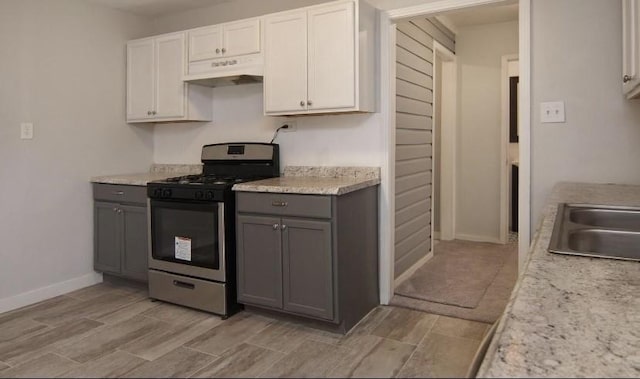 800 SE 16th St, Mineral Wells, TX 76067 - kitchen with stainless steel range with gas stovetop, under cabinet range hood, gray cabinetry, light countertops, and white cabinetry