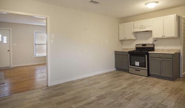 800 SE 16th St, Mineral Wells, TX 76067 - kitchen with stainless steel gas stove, under cabinet range hood, gray cabinets, and baseboards