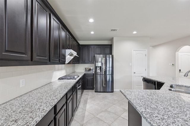 824 Water Garden Cir, Little Elm, TX 75068 - kitchen with appliances with stainless steel finishes, arched walkways, tasteful backsplash, extractor fan, and recessed lighting