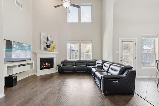 824 Water Garden Cir, Little Elm, TX 75068 - living area featuring a towering ceiling, ceiling fan, a warm lit fireplace, wood finished floors, and healthy amount of natural light