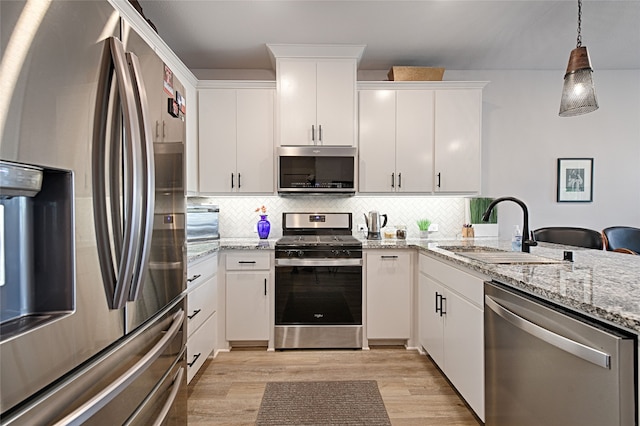 841 Emerling Dr, Mckinney, TX 75069 - kitchen featuring stainless steel appliances, a sink, light wood-style floors, backsplash, and white cabinetry