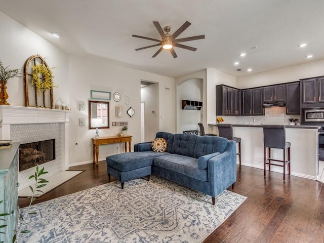 1676 Castle Pines Dr, Frisco, TX 75036 - living area featuring a ceiling fan, dark wood-style floors, a tiled fireplace, and recessed lighting
