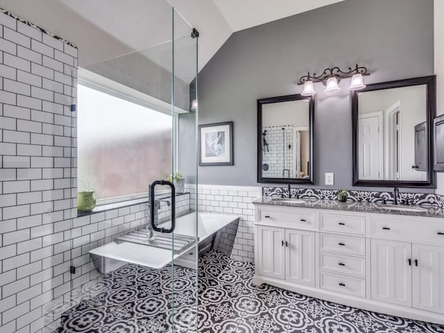 1676 Castle Pines Dr, Frisco, TX 75036 - bathroom featuring tile walls, double vanity, a soaking tub, tile patterned floors, and a wainscoted wall