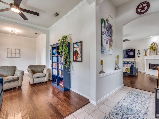 1676 Castle Pines Dr, Frisco, TX 75036 - living room with a ceiling fan, wood finished floors, arched walkways, a fireplace, and ornamental molding