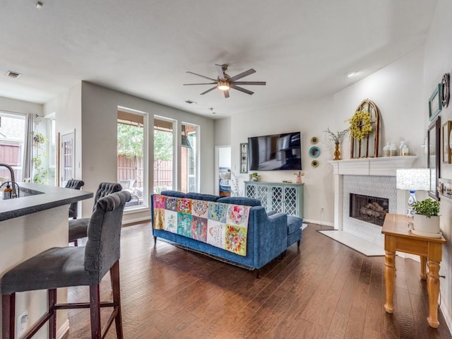 1676 Castle Pines Dr, Frisco, TX 75036 - living room with healthy amount of natural light, a ceiling fan, dark wood finished floors, and a fireplace