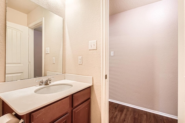 1112 Roman Dr, Princeton, TX 75407 - bathroom with wood finished floors, vanity, baseboards, and a textured wall