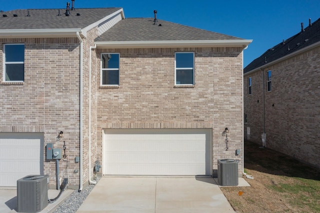 1808 Summer Aura, Mesquite, TX 75181 - back of house featuring an attached garage, central air condition unit, roof with shingles, and brick siding