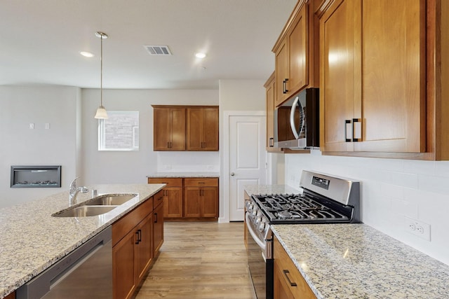 1804 Summer Aura, Mesquite, TX 75181 - kitchen with appliances with stainless steel finishes, a sink, brown cabinetry, light stone counters, and recessed lighting