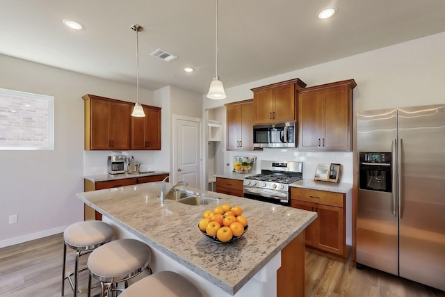 1804 Summer Aura, Mesquite, TX 75181 - kitchen with appliances with stainless steel finishes, a sink, a kitchen breakfast bar, brown cabinets, and light wood finished floors