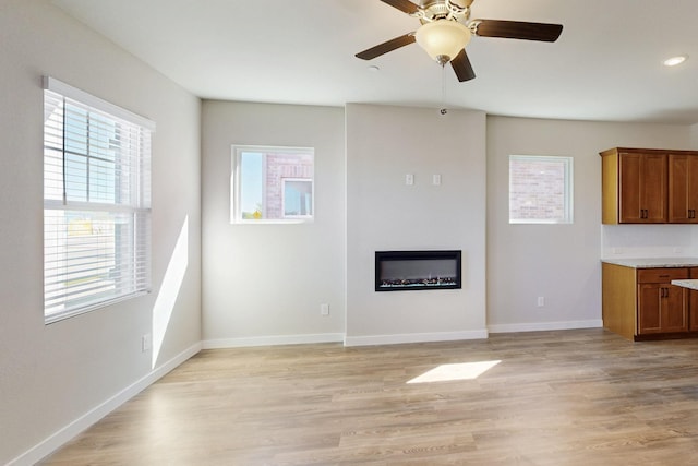 1804 Summer Aura, Mesquite, TX 75181 - unfurnished living room featuring plenty of natural light, a glass covered fireplace, light wood-style floors, ceiling fan, and recessed lighting