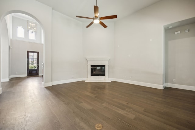 975 Stampede Dr, Frisco, TX 75036 - unfurnished living room with dark wood-style floors, a ceiling fan, a high ceiling, arched walkways, and a glass covered fireplace