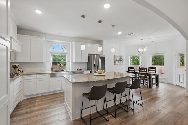 2821 White Plains Dr, Midlothian, TX 76065 - kitchen with stainless steel appliances, a sink, a center island, backsplash, and white cabinetry