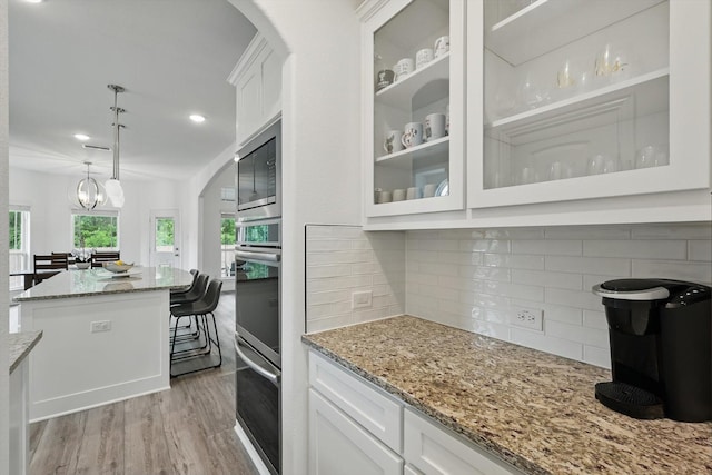 2821 White Plains Dr, Midlothian, TX 76065 - kitchen with light wood-type flooring, stainless steel appliances, white cabinets, arched walkways, and recessed lighting